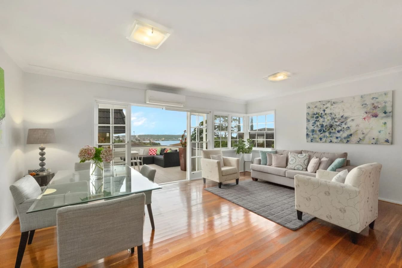 Living and dining room opening through French doors to a terrace overlooking North Harbour, Balgowlah