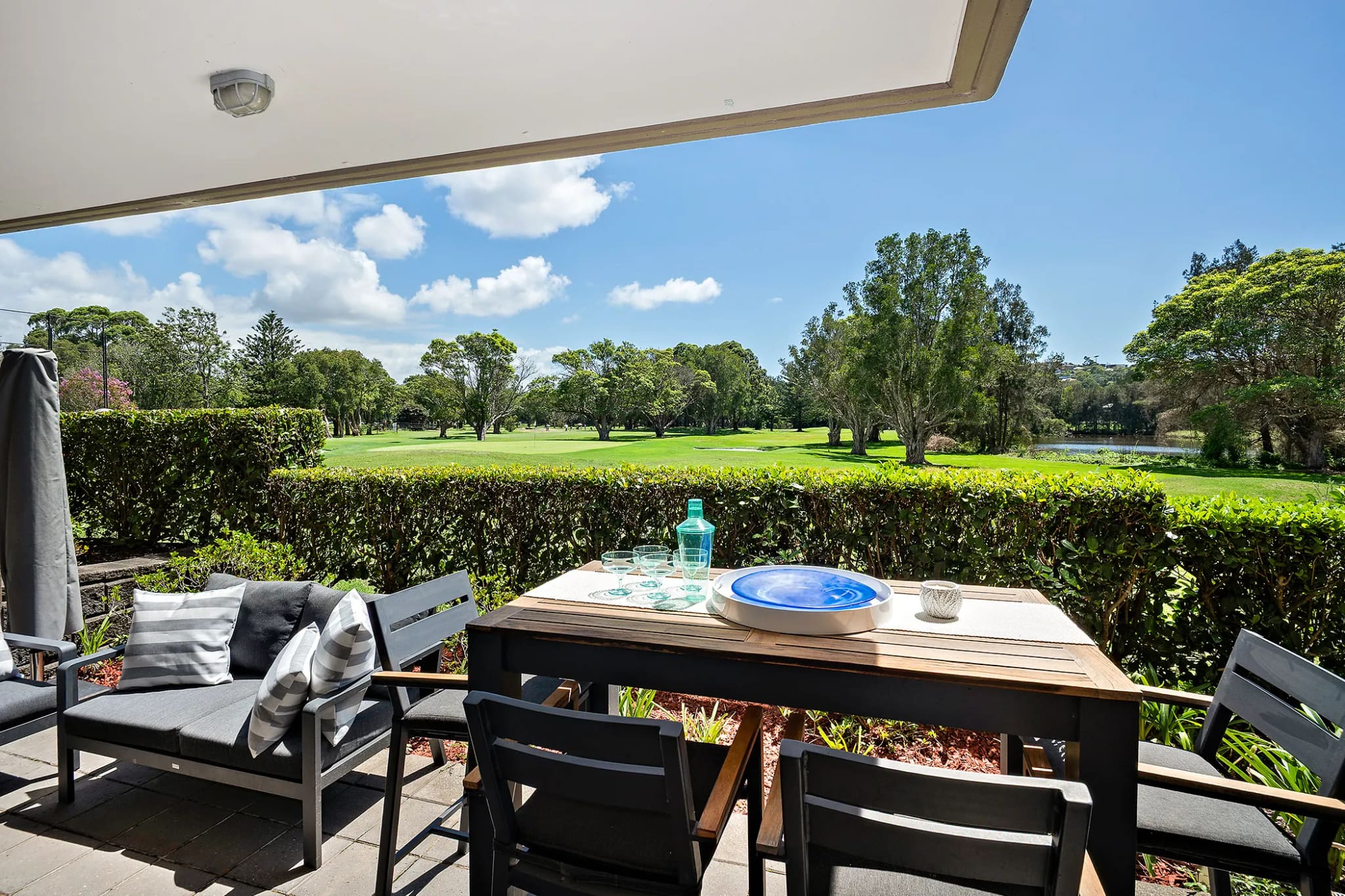Paved garden terrace with an outdoor dining setting, opening onto lawn and established trees, Manly Vale